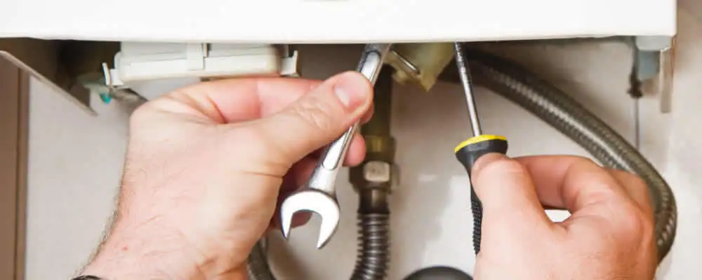 Boiler repair technician tightening pipe fittings and connections in San Diego, CA