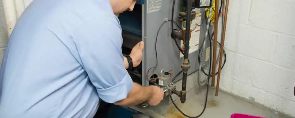 Furnace repair technician inspecting and servicing a home heating system in San Diego, CA
