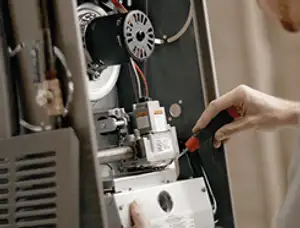 Furnace repair technician inspecting internal components and wiring in San Diego, CA