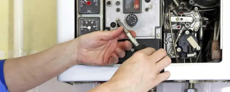Heating repair technician adjusting boiler controls and components in San Diego, CA