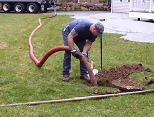 Septic pumping technician servicing a residential septic tank with a vacuum hose in San Diego, CA