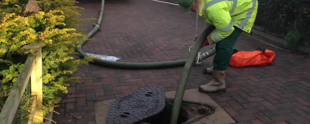 Septic tank cleaning technician servicing a septic tank with a vacuum hose in San Diego, CA