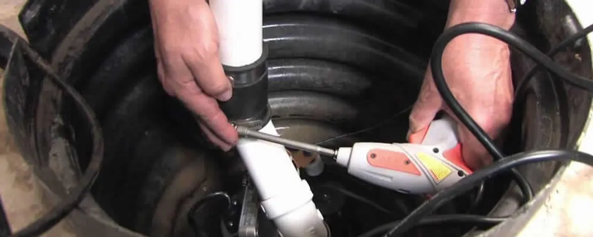 Sump pump installation technician connecting PVC discharge piping in San Diego, CA