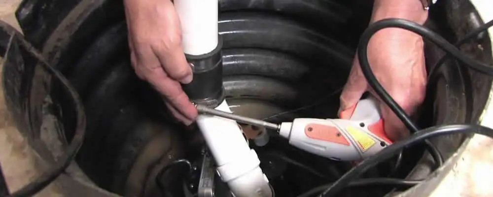 Sump pump installation technician connecting PVC discharge piping in San Diego, CA