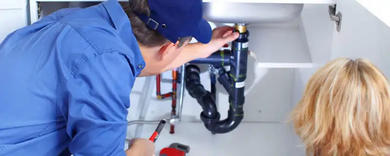 Plumber repairing under-sink drain pipes and fittings in San Diego, CA